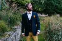 a bright outfit with mustard pants, a black waistcoat, a navy blazer, a colorful bow tie and navy shoes