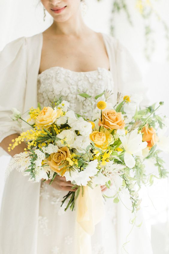 a bright wedding bouquet of yellow roses, white blooms, billy balls and mimosas, greenery and leaves is a catchy idea for spring