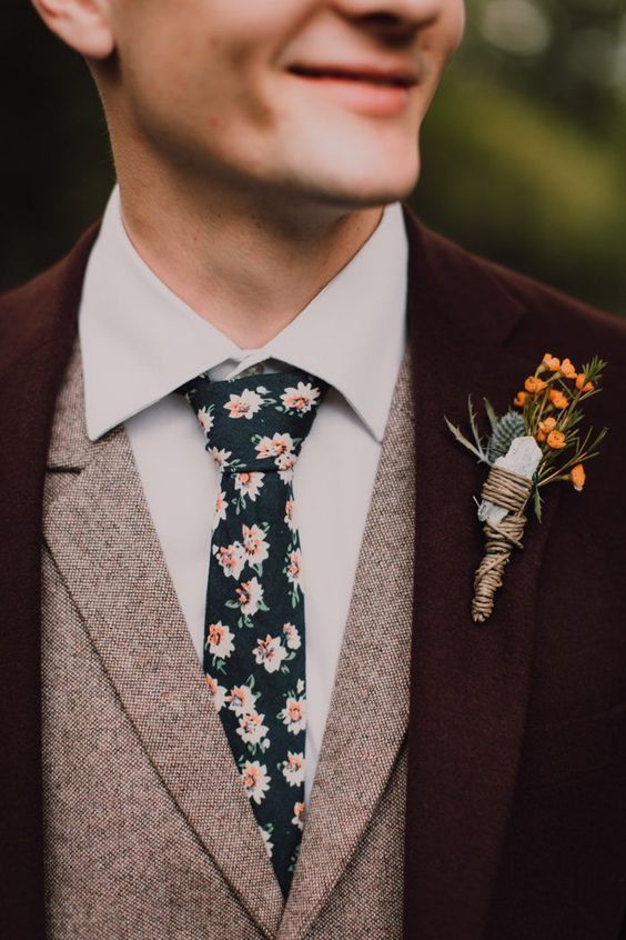 a burgundy pantsuit, a grey waistcoat, a white shirt, a moody floral tie and a chic floral boutonniere are a super cool combo for a fall boho wedding