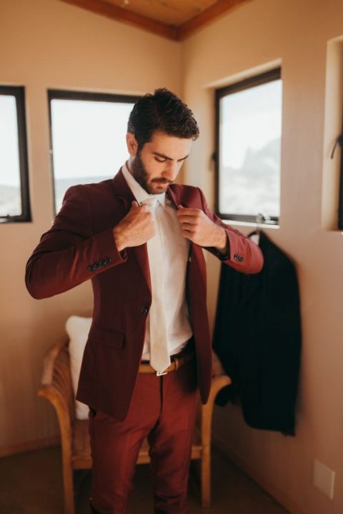 a burgundy suit, a white shirt and a white tie for a jewel-toned fall groom's look