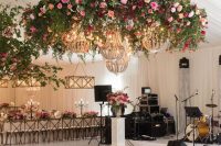 a chic and glam wedding dance floor with painted blooms and monograms, with a greenery chandelier with brights blooms and glam beaded chandeliers
