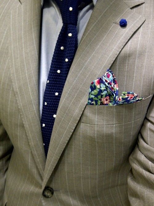 a chic groom's look with a tan striped suit, a white shirt, a navy and white polka dot tie and a bright floral handkerchief