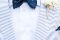 a coastal groom’s look with a blue thin striped blazer, a white shirt, a navy and green polka dot bow tie