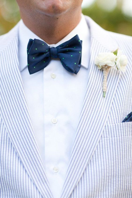 a coastal groom's look with a blue thin striped blazer, a white shirt, a navy and green polka dot bow tie