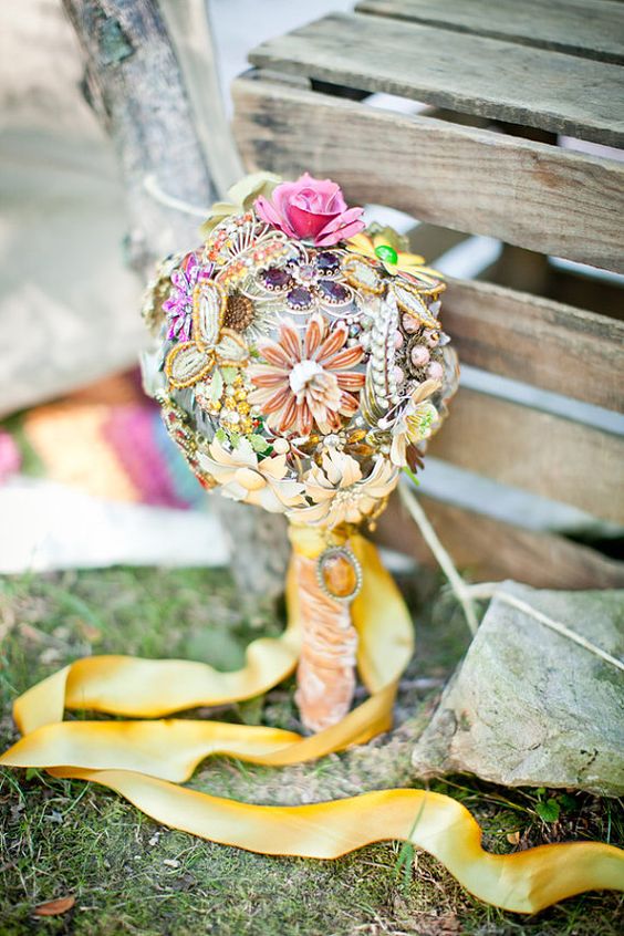 a colorful brooch wedding bouquet in all the bright colors with a long yellow silk wrap and ribbons