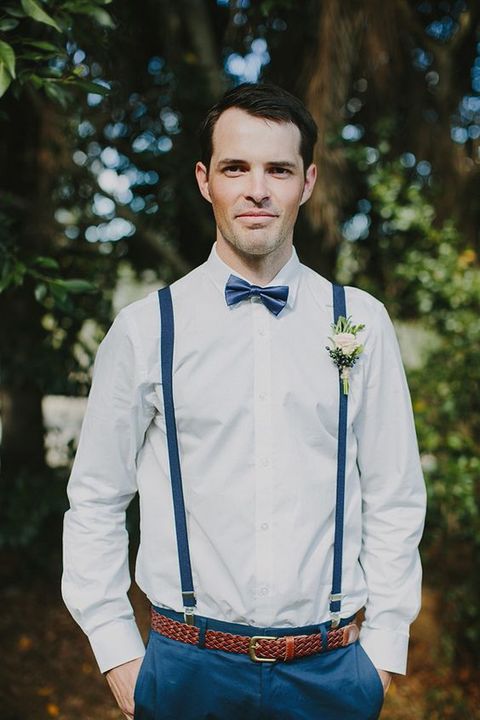 a creative and elegant groom's outfit with a white shirt, navy suspenders, a navy bow tie and pants