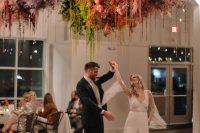 a dance floor accented with a fantastic colorful overhead installation of pampas grass and some hanging parts is gorgeous