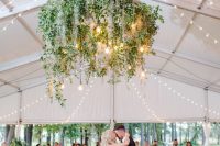 a dance floor styled with a large greeneyr chandelier with lights and bulbs over it is a lovely idea for an organic space