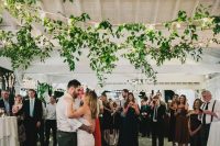 a dance floor styled with greenery garlands and bulbs is a lovely idea for a more relaxed and casual wedding