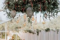 a dance floor styled with grey tiles, an oversized chandelier with greenery and bright blooms, pendant bulbs and drop-shaped chandeliers