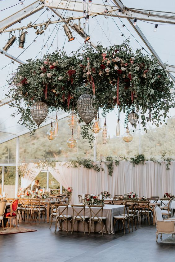a dance floor styled with grey tiles, an oversized chandelier with greenery and bright blooms, pendant bulbs and drop shaped chandeliers