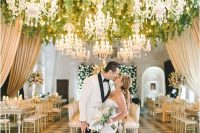 a glam and sophisticated dance floor in gold and white, with greenery, lights and chic chandeliers all over the dance floor is fabulous