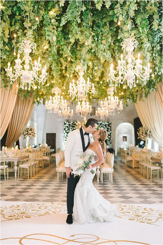 a glam and sophisticated dance floor in gold and white, with greenery, lights and chic chandeliers all over the dance floor is fabulous