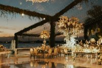 a glam dance floor with a glossy cover and monograms, an oversized chandelier and string lights over the space