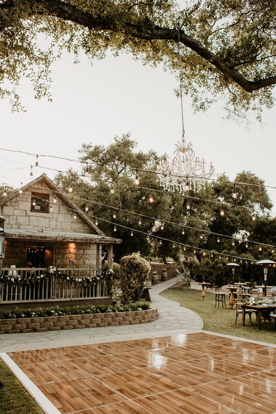 a glossy outdoor dance floor with string lights and a crystal chandelier over it is a lovely and cool solution for a relaxed wedding