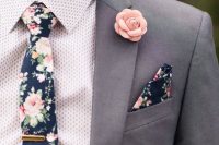 a grey pantsuit, a printed shirt, a moody floral tie and a matching handkerchief, a pink fabric bloom boutonniere are great for summer