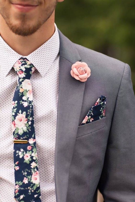 a grey pantsuit, a printed shirt, a moody floral tie and a matching handkerchief, a pink fabric bloom boutonniere are great for summer