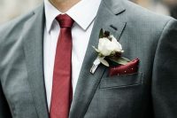 a grey pantsuit, a white shirt and a burgundy tie plus a burgundy handkerchief and a white floral boutonniere