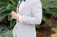 a grey thin striped suit, a pink shirt and a navy and green striped bow tie for a bold and fun outfit at the wedding
