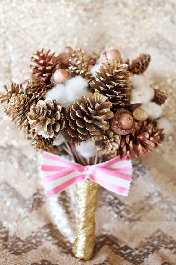 a holiday wedding bouquet with gilded pinecone,s cotton, acorns, a gold glitter wrap and a striped pink bow