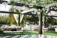 a modern glossy dance floor in grey and white, with greenery and multiple clear pendant lamps is a chic and cool idea for a modern wedding