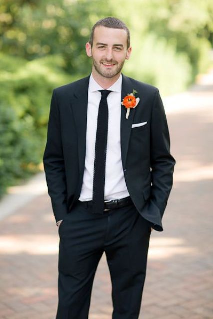 a modern groom's outfit with a black pantsuit, a white shirt and a black skinny tie, a bright floral boutonniere is a great idea for the fall