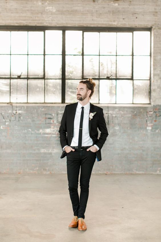 a modern groom's outfit with a black suit, a white shirt, a black skinny tie, amber shoes and a neutral floral boutonniere is cool