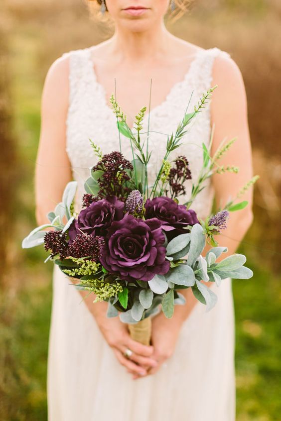 a moody fall wedding bouquet with greenery and deep purple roses and blooms