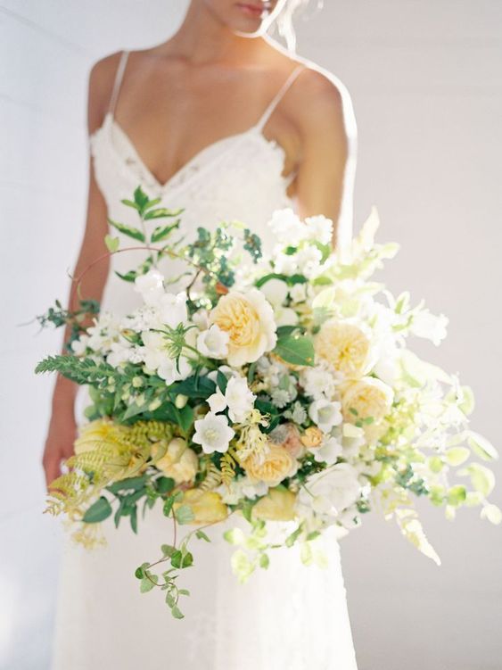 a pale yellow wedding bouquet that includes peony roses, lots of greenery and leaves is a beautiful idea for spring