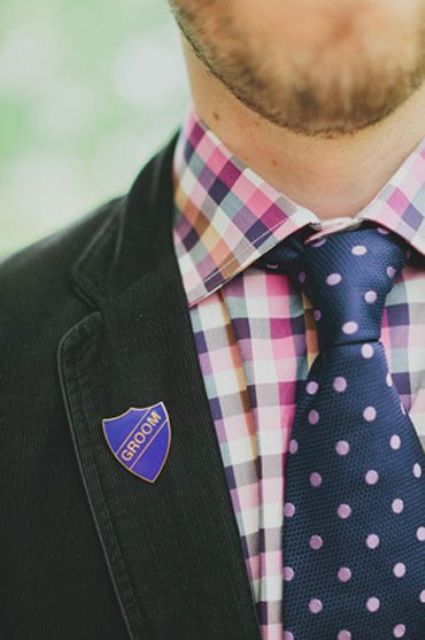 a pretty and bright groom's outfit with a colorful checked shirt, a navy and pink polka dot tie and a black blazer