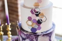 a purple and metallic wedding cake with hexagons and a marble effect
