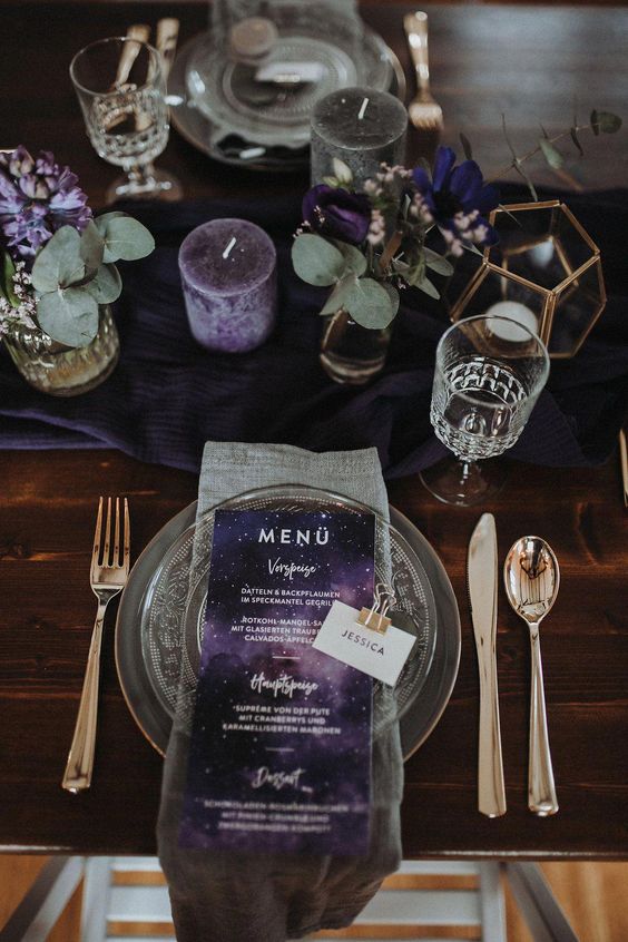 a purple nd grey wedding tablescape with purple candles, blooms and menus and calmer grey shades