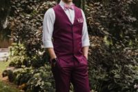 a purple suit with a waistcoat, a white shirt and a pink bow tie for a whimsical and statement groom’s look