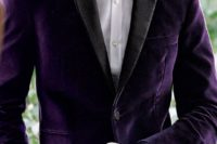 a purple velvet tux with black lapels is a refined and chic groom’s outfit idea