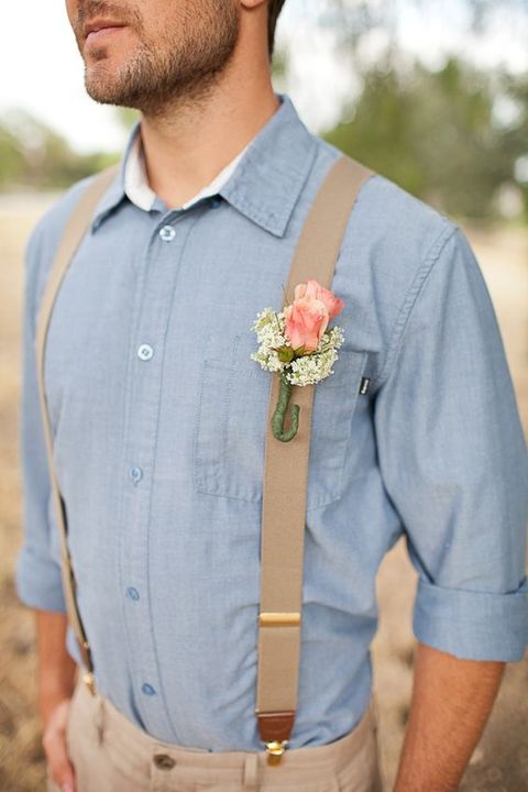 a rustic groom's outfit with tan pants, tan suspenders, a chambray shirt and a floral boutonniere