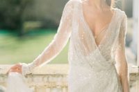 a shiny white wrap wedding dress with a deep neckline, long sleeves and a thihg high slit