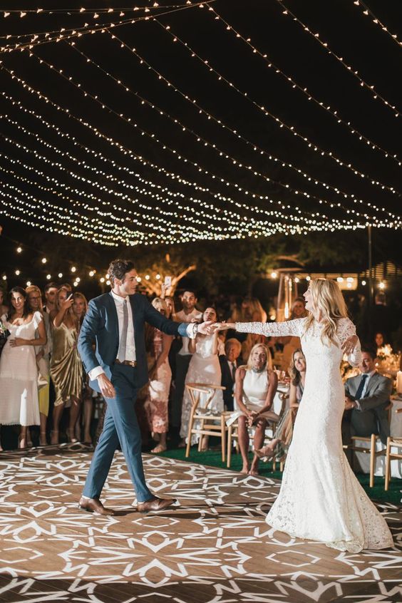 a simple and rustic dance floor with floral stencilling and string lights over the space is amazing for a rustic wedding