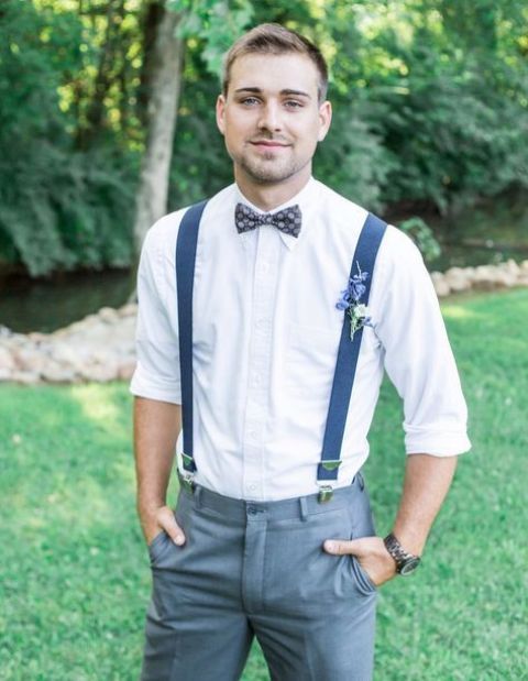 a simple groom's outfit with a white shirt, grey pants, navy suspenders and a printed bow tie for a bolder look
