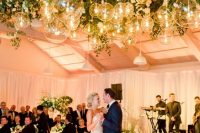 a sophisticated wedding dance floor with white blooms around and over it, with greenery and clear glass sphere pendant lamps is amazing