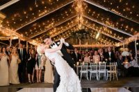 a stylish and chic dance floor in black and white, with a greenery and white flower chandelier and lights over it is a lovely idea