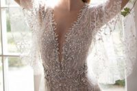 a super shiny silver sheath wedding gown with a plunging neckline, wide airy sleeves and a train