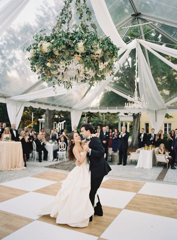 a vintage dance floor in beige and white, with a lovely greenery and white bloom chandelier with additional crystal touches