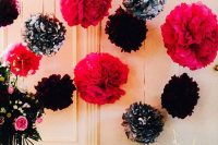 a wedding card table accented with fuchsia, black and black and white paper pompoms hanging over the table