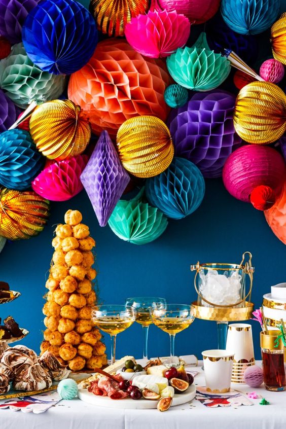 a wedding dessert table highlit with a super colorful honeycomb paper pompom wedding garland to make it feel fun