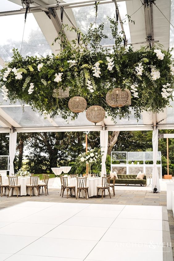 a white tile dance floor with an oversized greenery chandelier, white rochids and sphere chandeliers is amazing