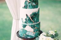 a white wedding cake decorated with emerald agates with a copper edge is a bold modern idea
