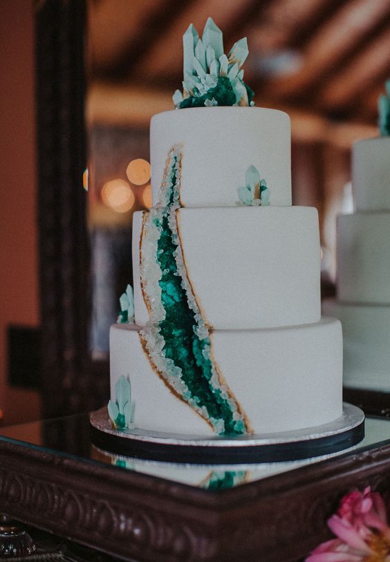 a white wedding cake decorated with emerald geodes is a very edgy idea to try for a modern wedding