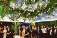 a white wedding dance floor accented with an oversized square greenery chandelier with white blooms is amazing