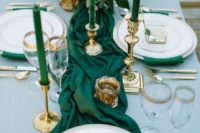 an emerald green table runner and matching candles plus gilded touches and a white bloom centerpiece