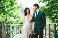 an emerald groom’s suit paired with a navy tie, brown shoes and a white shirt for a bold modern look